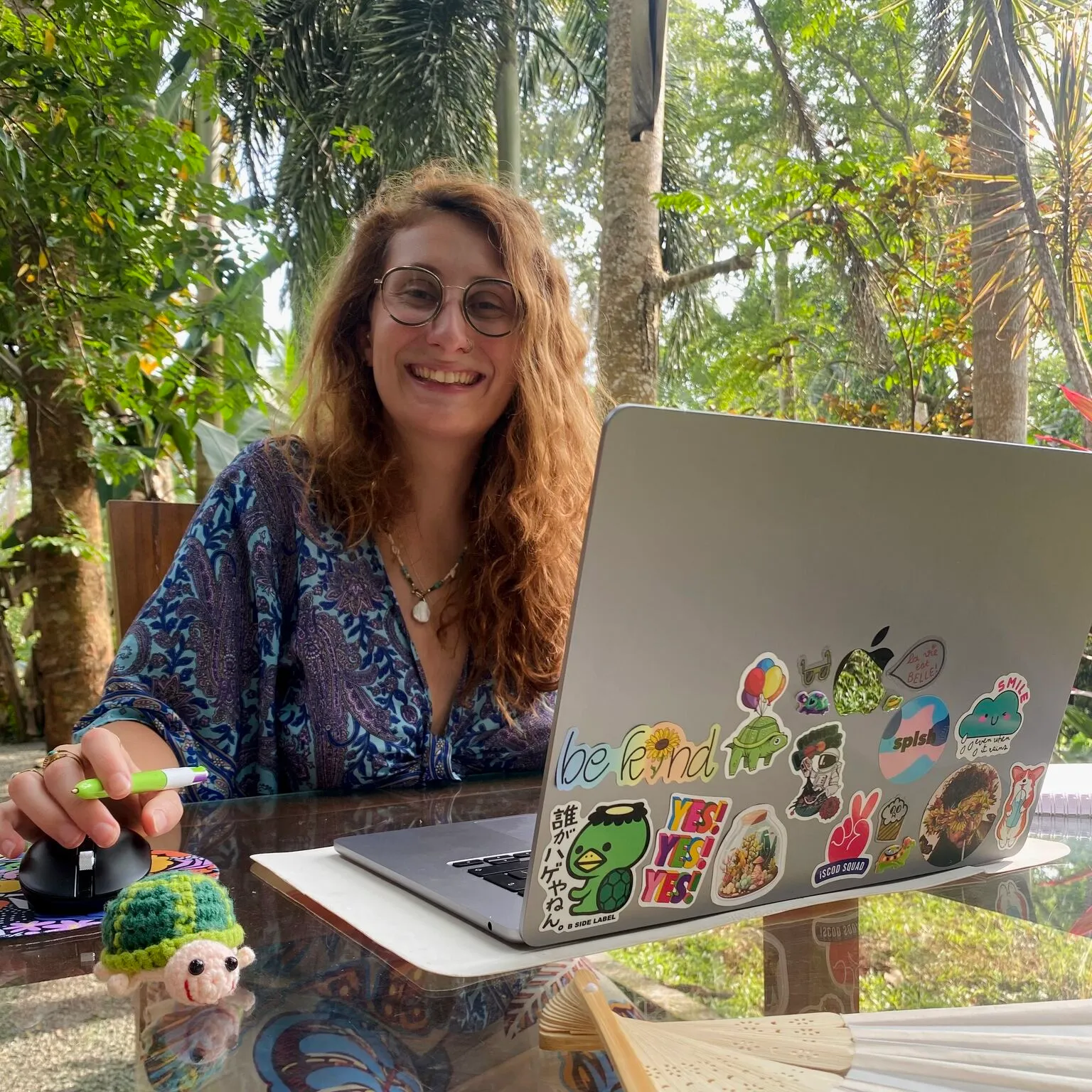 Juliette Drumain, graphiste, souriante devant son ordinateur portable.
